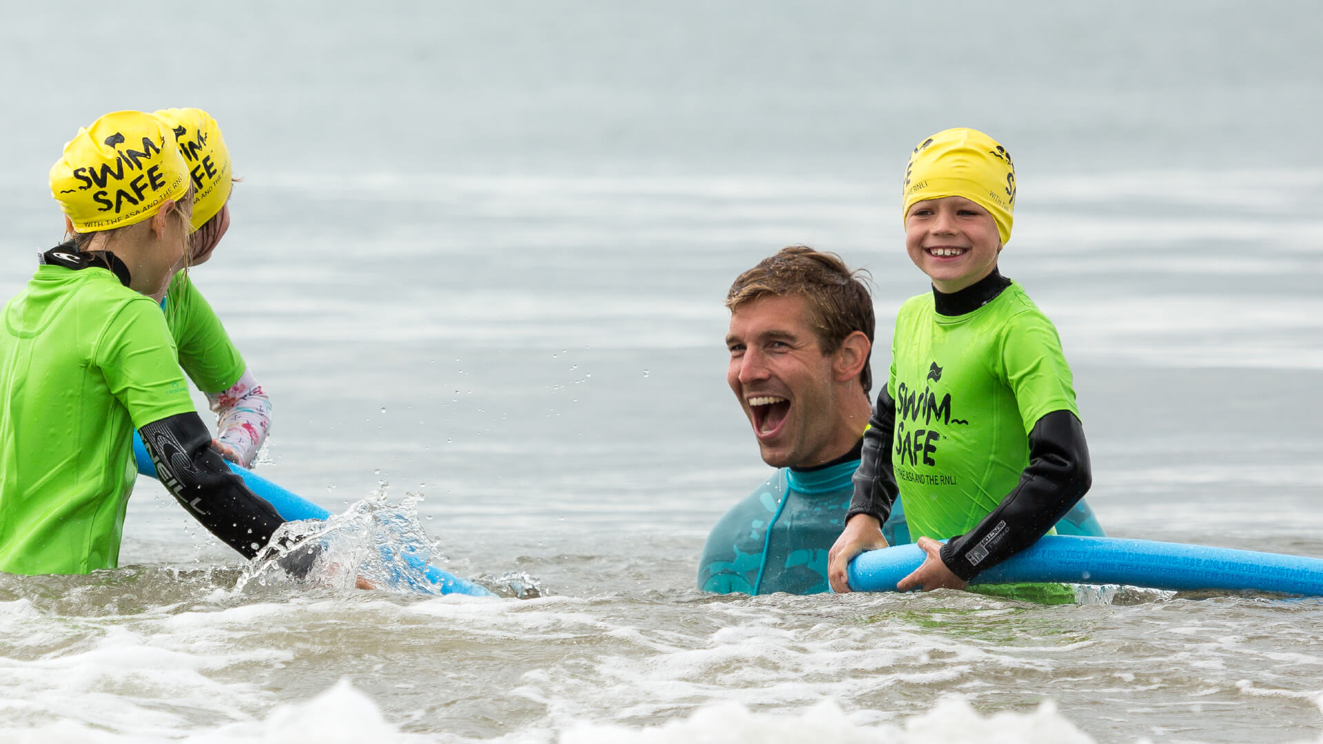 Three children having fun in the sea with a Swim Safe instructor in Boscombe, Dorset