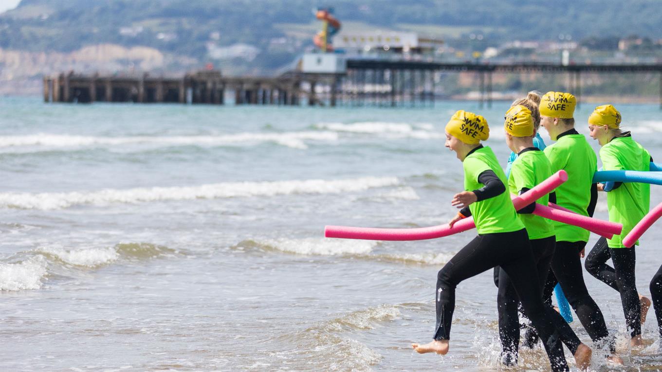 Children taking part in a Swim Safe session on a beach