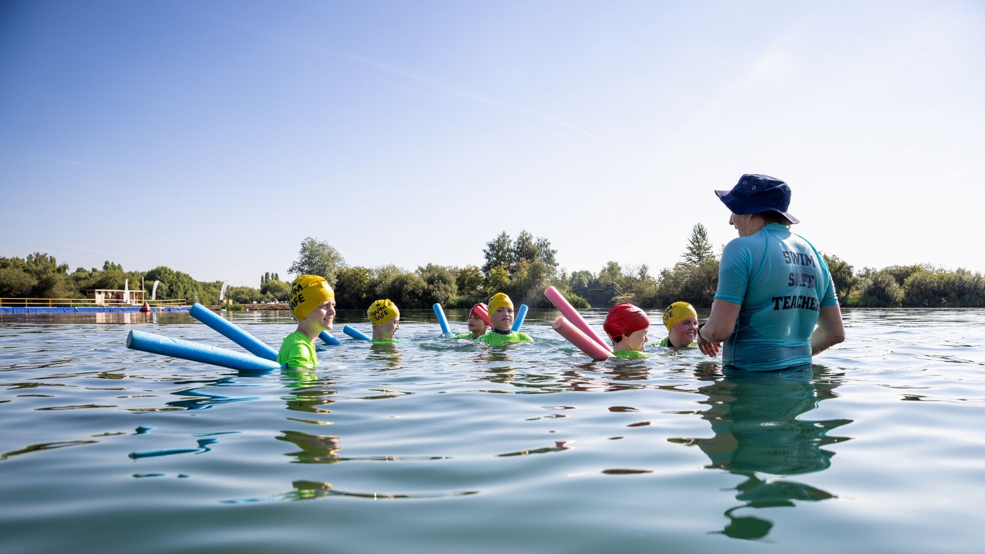 Children and a teacher standing in shallow water during an activity