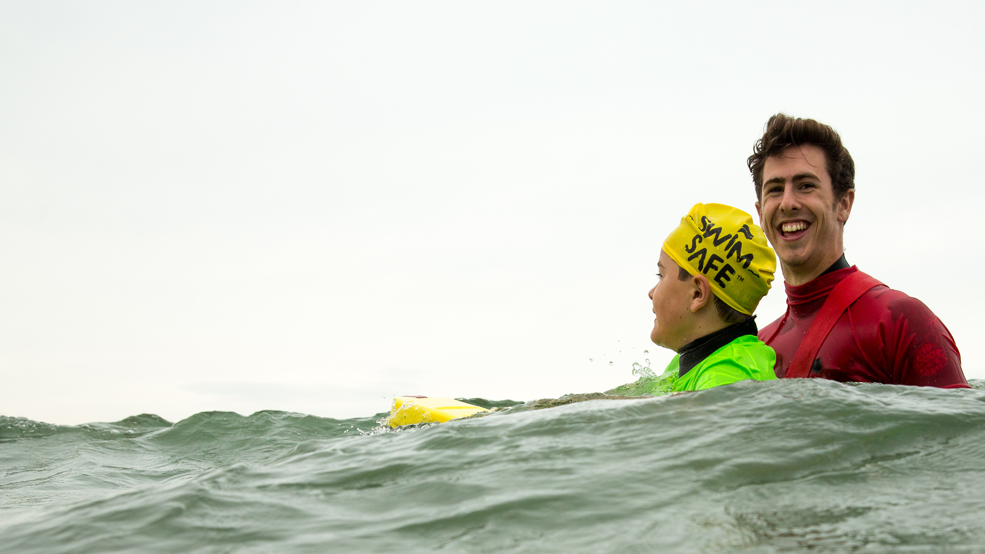 A Swim Safe instructor supports a young boy at Poole's Shore Road beach as she learns to float