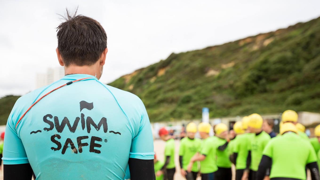 An RNLI Swim Safe instructor stands on Boscombe beach